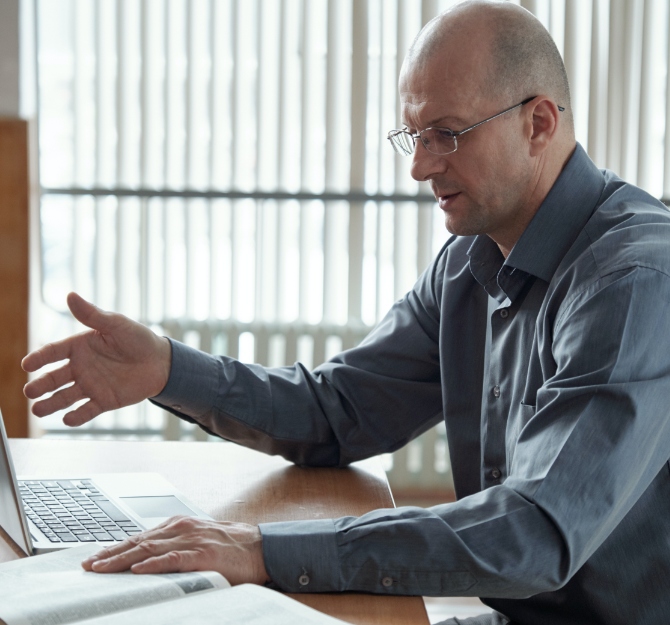 bald-professor-in-shirt-and-eyeglasses-sitting-by-computer